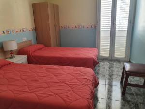 2 camas en una habitación con sábanas rojas y una silla en Ca La Miquela, en Albagés