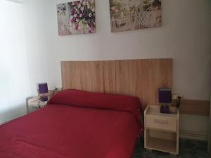 um quarto com uma cama vermelha e 2 candeeiros nas mesas em Ca La Miquela em Albagés