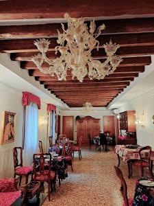 Locanda Ca' Formosa في البندقية: غرفة طعام فيها ثريا وطاولات وكراسي