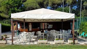 Campeggio Bocca di Cecina في مارينا دي سيسينا: جناح بطاولات وكراسي في حديقة