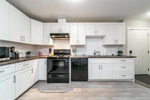 a kitchen with white cabinets and a black dishwasher at Executive Home - Long Stays Welcome - Garage Parking - Free WiFi & Netflix in Edmonton