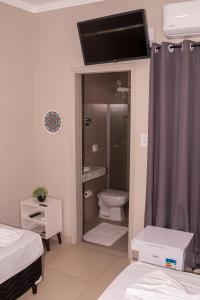 a bathroom with a toilet and a tv on the wall at Premier Hotel in Votuporanga