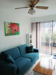 a blue couch in a living room with a ceiling fan at Duplex du Bois d'Amour in Quimper