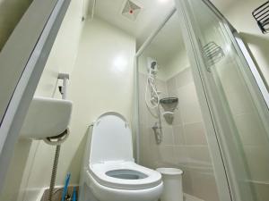 een kleine badkamer met een toilet en een douche bij Cool Breeze Brenthill Deluxe in Baguio