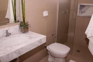 a bathroom with a toilet and a sink and a shower at Premier Hotel in Votuporanga