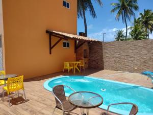 a pool with chairs and tables next to a house at Apart. japaratinga in Japaratinga