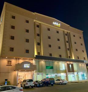 a hotel building with cars parked in front of it at Amaken Aparthotel in Al Hofuf
