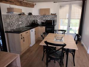 uma cozinha com mesa e cadeiras num quarto em LE BON’HEURE em Abilly-Sur-Claise