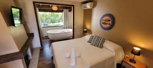 a bathroom with a bed and a tub and a sink at Pousada Capitão Cook in Praia do Rosa