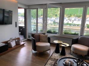 a living room with chairs and a tv and windows at Moselapart in Cochem