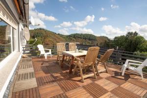 a wooden deck with a table and chairs on a balcony at Eifel Ferienhaus Mirjam in Manderscheid