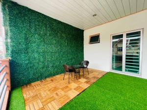 a room with a green wall with chairs and a table at RJ Homey Guesthouse in Sungai Petani