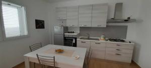 een keuken met witte kasten en een tafel met stoelen bij Appartamento 2 con piscina in Caltagirone