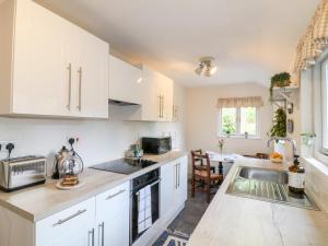 a kitchen with white cabinets and a sink at 16 Long Row in Belper