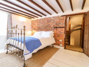 a bedroom with a bed and a brick wall at 16 Long Row in Belper