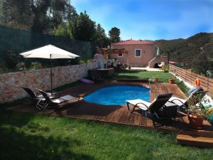 a pool with chairs and an umbrella in a yard at Ampelos Cretan Villa - Private Pool & Heated Ozone Jacuzzi in Yerolákkos