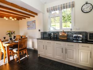 a kitchen and dining room with a table and a clock at Orchard Cottage in Ashbourne