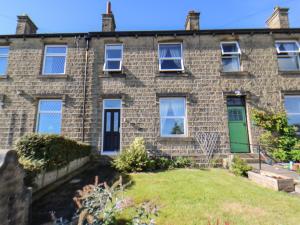 an old brick house with a green door and a yard at Olive Tree Cottage in Holmfirth