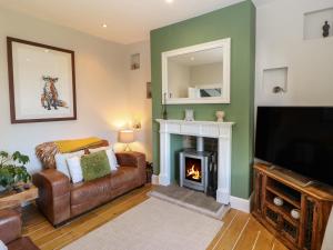 a living room with a fireplace and a television at Olive Tree Cottage in Holmfirth