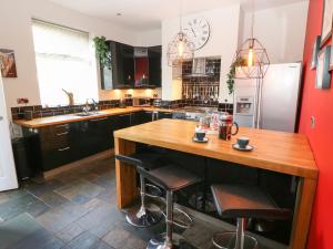 una cocina con una isla de madera con taburetes de bar en Olive Tree Cottage, en Holmfirth