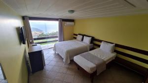 a hotel room with two beds and a balcony at Pousada Mirante dos Papagaios in Búzios