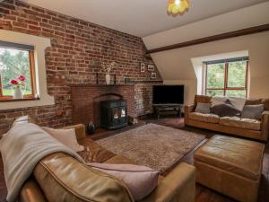 uma sala de estar com um sofá e uma parede de tijolos em Owlbury Hall Barn em Montgomery
