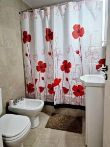 a bathroom with a toilet and a shower curtain with red flowers at Corazón de Flores in Buenos Aires