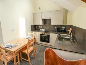 a small kitchen with a wooden table and chairs at Llety Cariad - 2 Plough & Harrow in Cowbridge