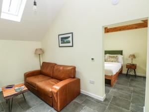 a living room with a leather couch and a bed at Llety Cariad - 2 Plough & Harrow in Cowbridge