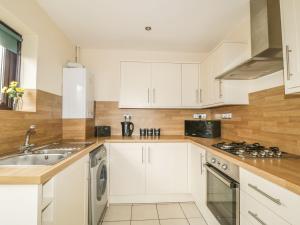 a kitchen with white cabinets and a sink at Croft House Cottage in Penrith