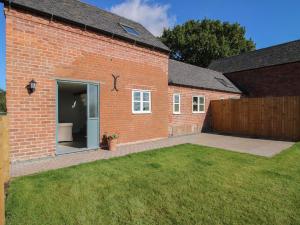 a brick house with a patio and a yard at Cow'ouse in Shrewsbury