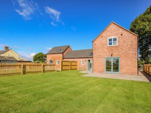 a brick house with a fence and a yard at The Barn in Shrewsbury