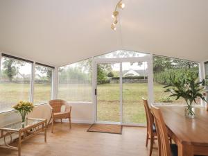 a dining room with a table and chairs and windows at Garden Cottage in Muir of Ord