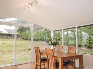 a dining room with a table and chairs and windows at Garden Cottage in Muir of Ord