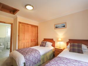 1 dormitorio con 2 camas y baño en Garden Lodge en Muir of Ord