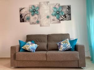 eine Couch in einem Wohnzimmer mit vier Gemälden an der Wand in der Unterkunft Adosado playa, geoda y Aguilas cerca, con barbacoa y piscina en San Juan de los terreros in San Juan de los Terreros