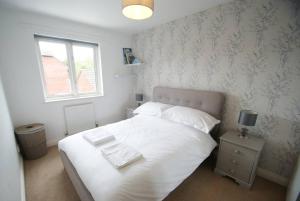 1 dormitorio con cama blanca y ventana en Cosy Family Home Near the Quay en Exeter