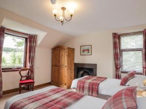 a bedroom with two beds and a fireplace at Balloan House in Muir of Ord