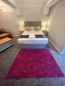 a bedroom with a large bed with a pink rug at Y Teifi in Llandysul