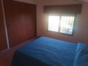 Un dormitorio con una cama azul y una ventana en Cabañas Akumali en Nono