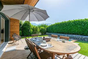 een houten terras met een tafel en een parasol bij Maison BOOA in Sévrier