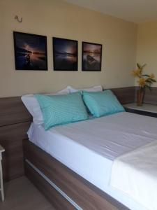 a bedroom with a bed with four pictures on the wall at Porto das Dunas Solarium Residence in Aquiraz