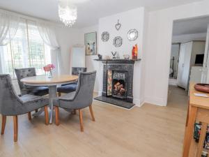 a dining room with a table and a fireplace at Llidiart Cerrig in Dyserth