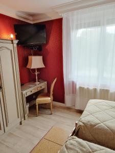 1 dormitorio con 1 cama y escritorio con TV en l'Auberge des Gourmets Hôtel Restaurant en Le Vaudioux