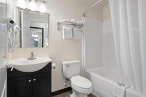 a white bathroom with a sink and a toilet and a shower at Beach Bum Inn in Ocean City