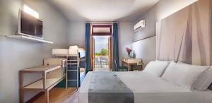 a bedroom with a bed and a desk and a window at Hotel Baia Imperiale in Campo nell'Elba