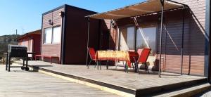 a deck with a table and chairs on a house at Cabaña Girasol - Cocina Parking Piscina Wifi in Algarrobito