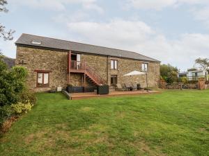 a stone house with a deck and lawn at The Hayloft in Kingsbridge