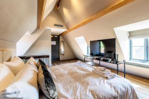 a bedroom with a large white bed and a tv at Bistrotel 't Amsterdammertje in Nieuwersluis