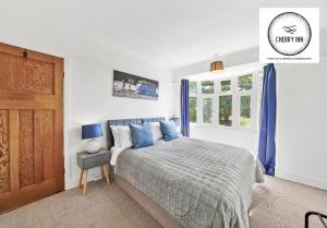 a bedroom with a bed with blue pillows and a door at 3 Bedroom House with Parking & Garden By Cherry Inn Short Lets & Serviced Accommodation Cambridge in Cambridge